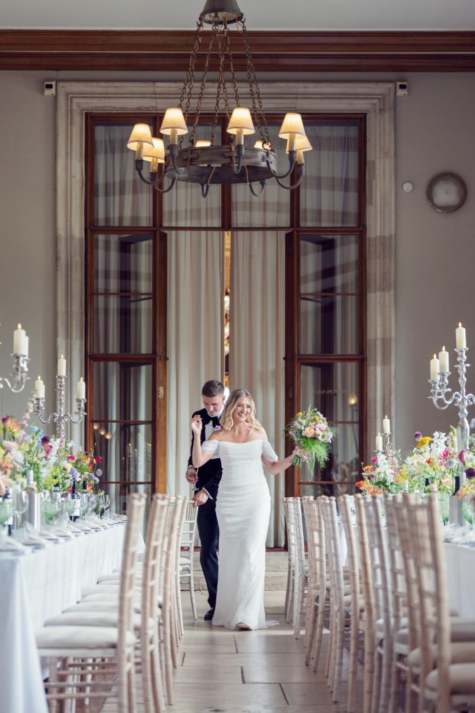 A man and woman walking down a long hallway.